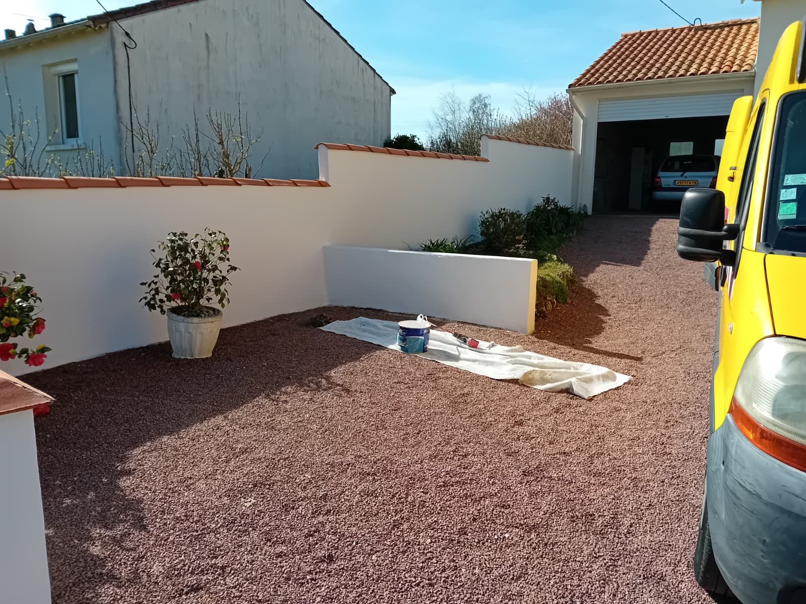 Cour aménagée avec gravier neuf et murets bas enduits en blanc